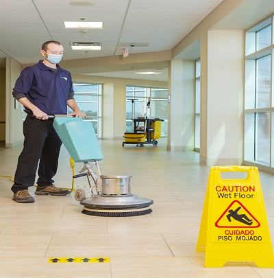 Cleaning person buffing a tile floor